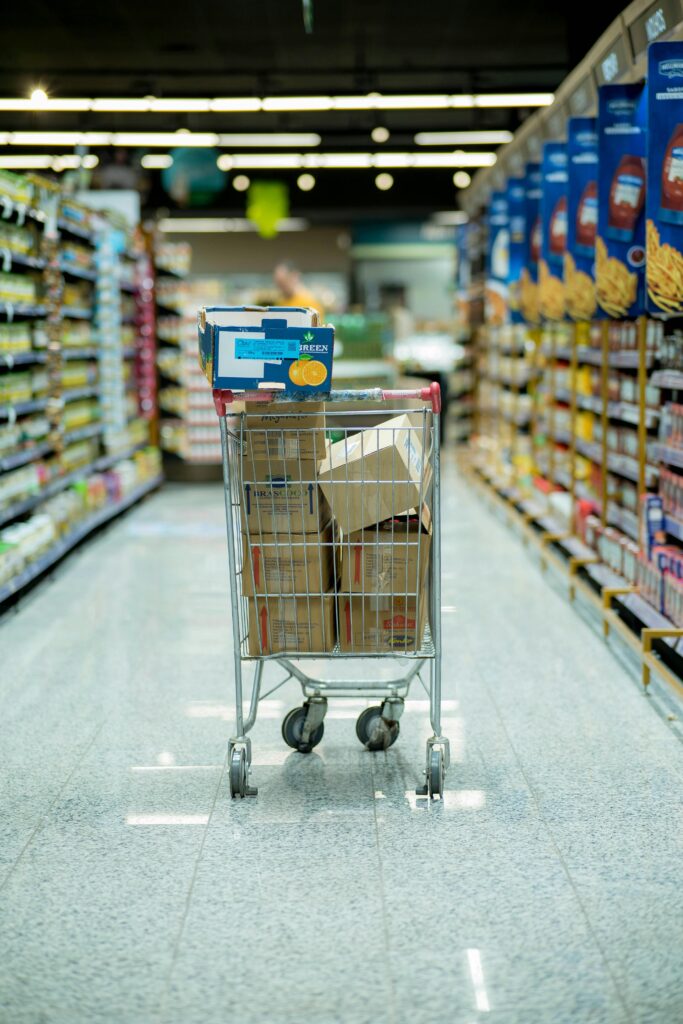 pexels-photo-15491800-15491800 A shopping cart with packages in a grocery aisle, showcasing everyday shopping options.