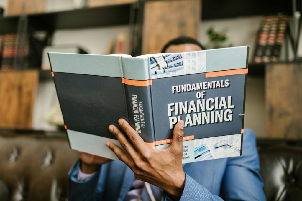 pexels-photo-7821487-7821487 A professional individual in a suit reading 'Fundamentals of Financial Planning' indoors.
